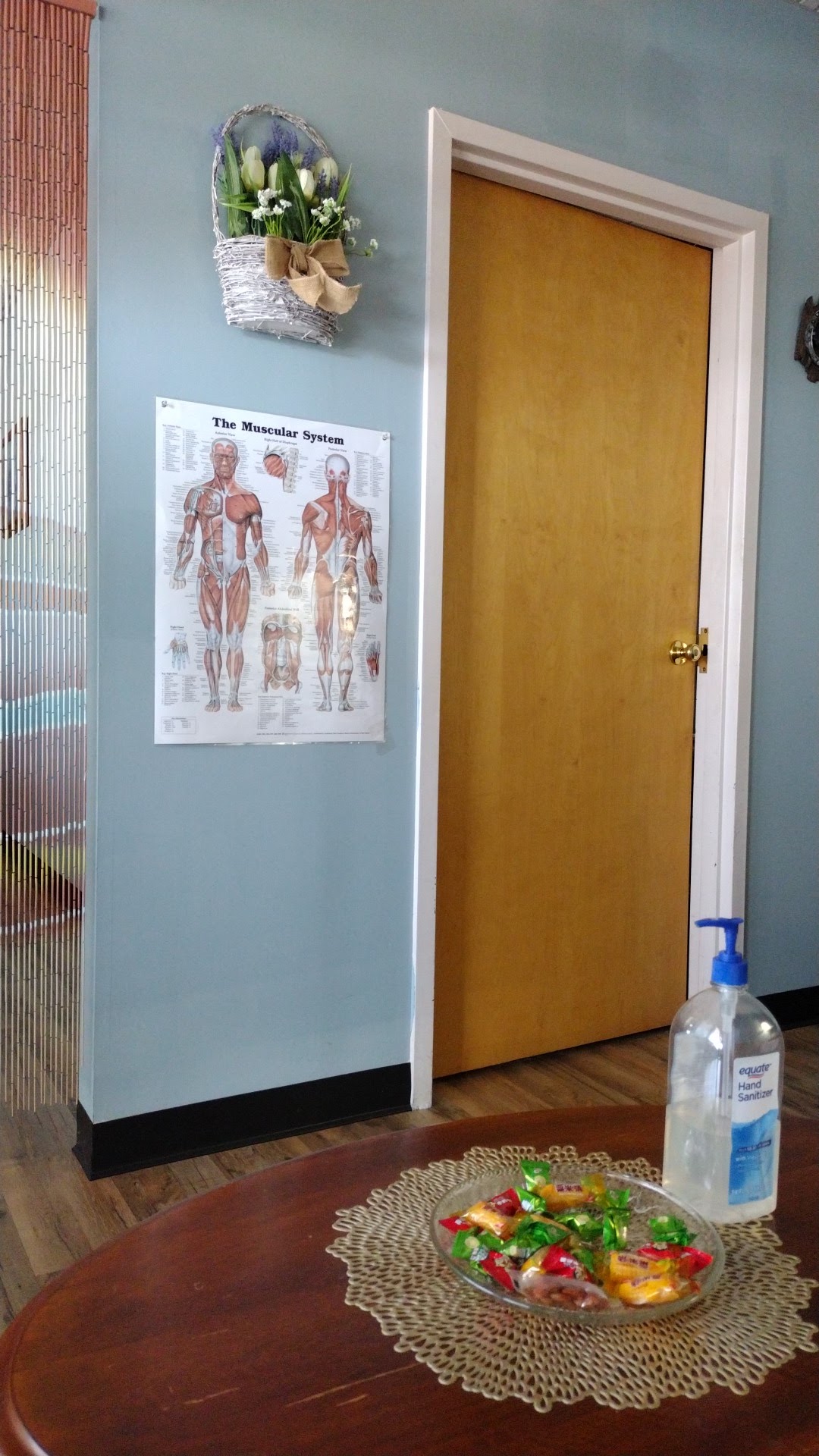 A bowl of candy and hand sanitizer in the lobby beside a muscular system chart