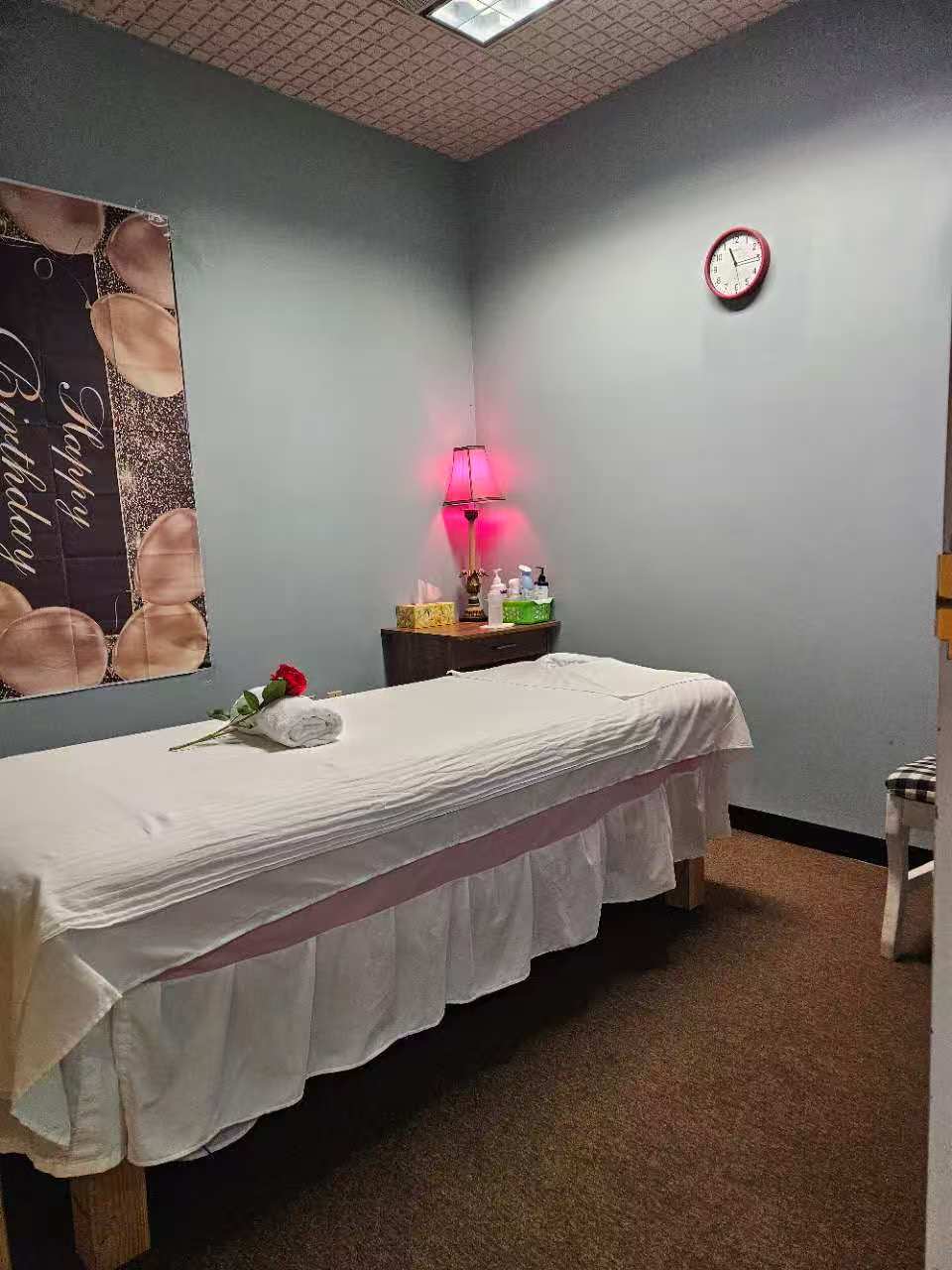 Massage table with a rolled towel and a red rose