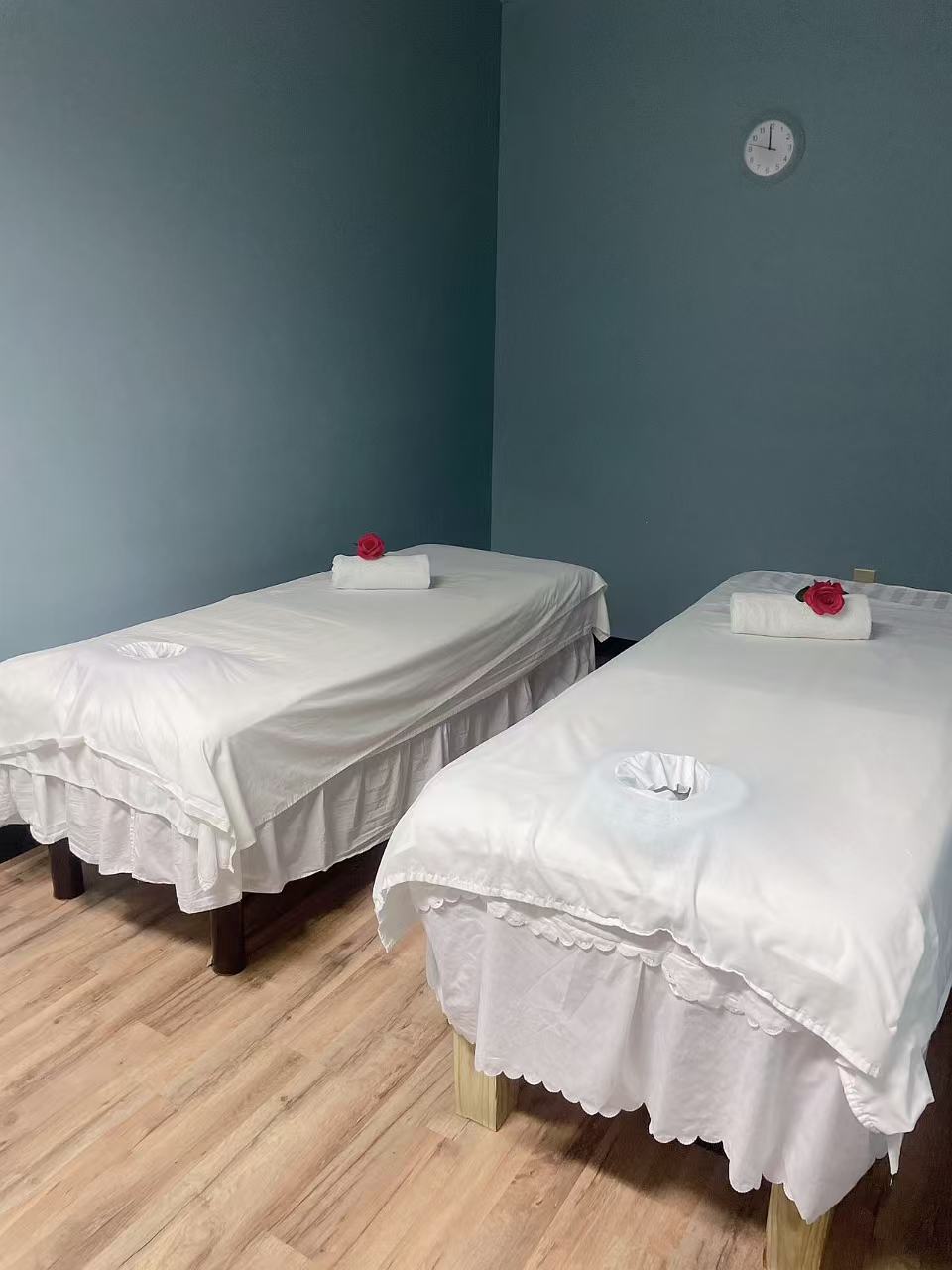 Two massage tables made up with white linens and a rose on each towel